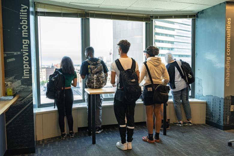 A group of students peer out a window.
